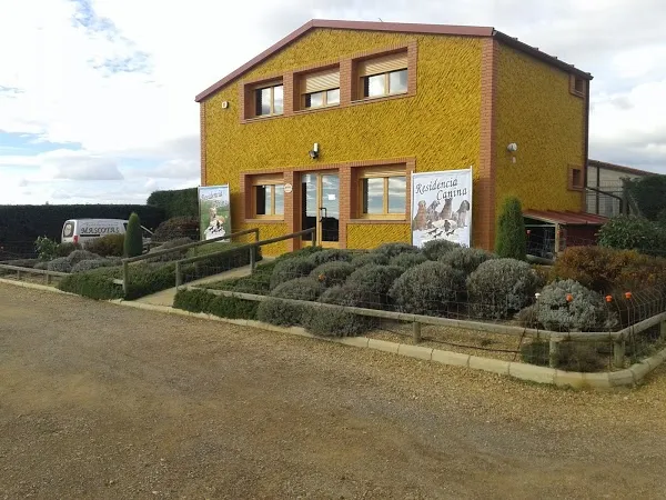 Fachada exterior de Residencia Canina SERINMAS en Villanueva del Carnero, León, edificio amarillo con jardín